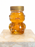 Small bear-shaped jar of golden honey with gold cap